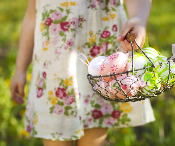 Close up of colorful Easter eggs in a basket in hands of a little girl